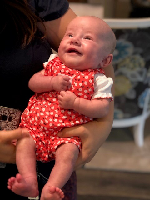 Smiling baby wearing a red outfit